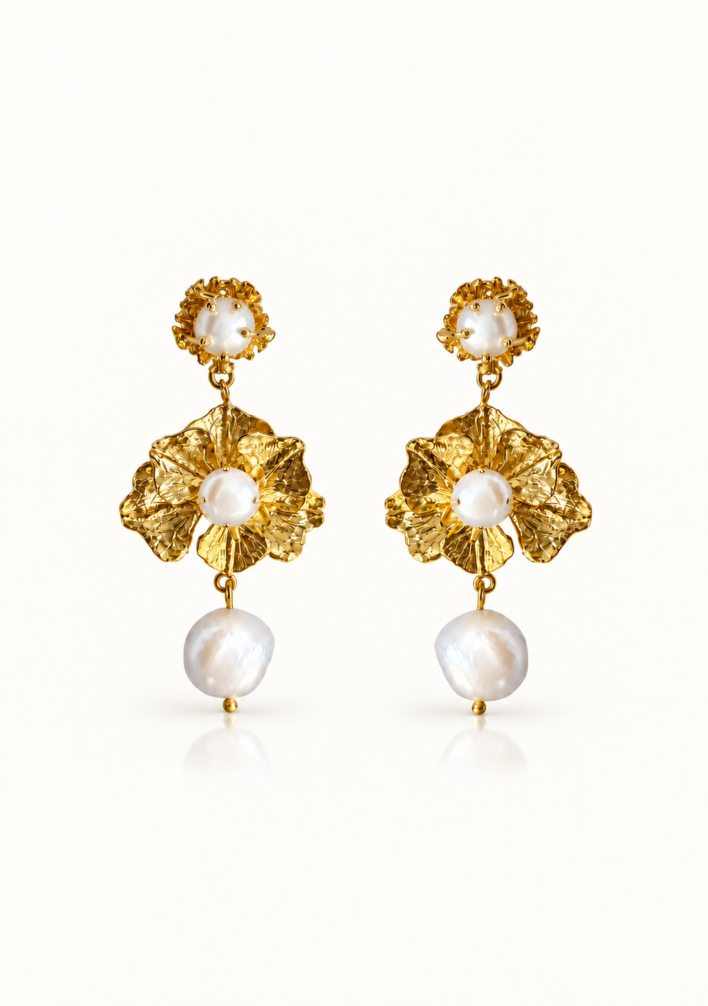 A pair of gold and white pearl drop earrings with textured gold floral elements and large irregular white pearls, shown on a clean white background.