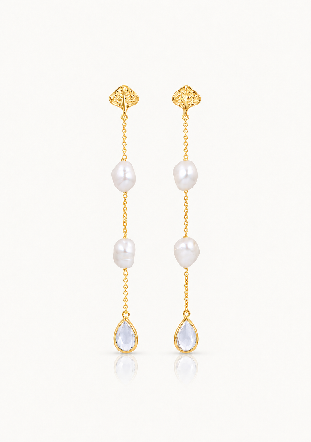 A pair of gold pearl dangle earrings with irregular white baroque pearls and teardrop-shaped clear stones, shown on a clean white background.