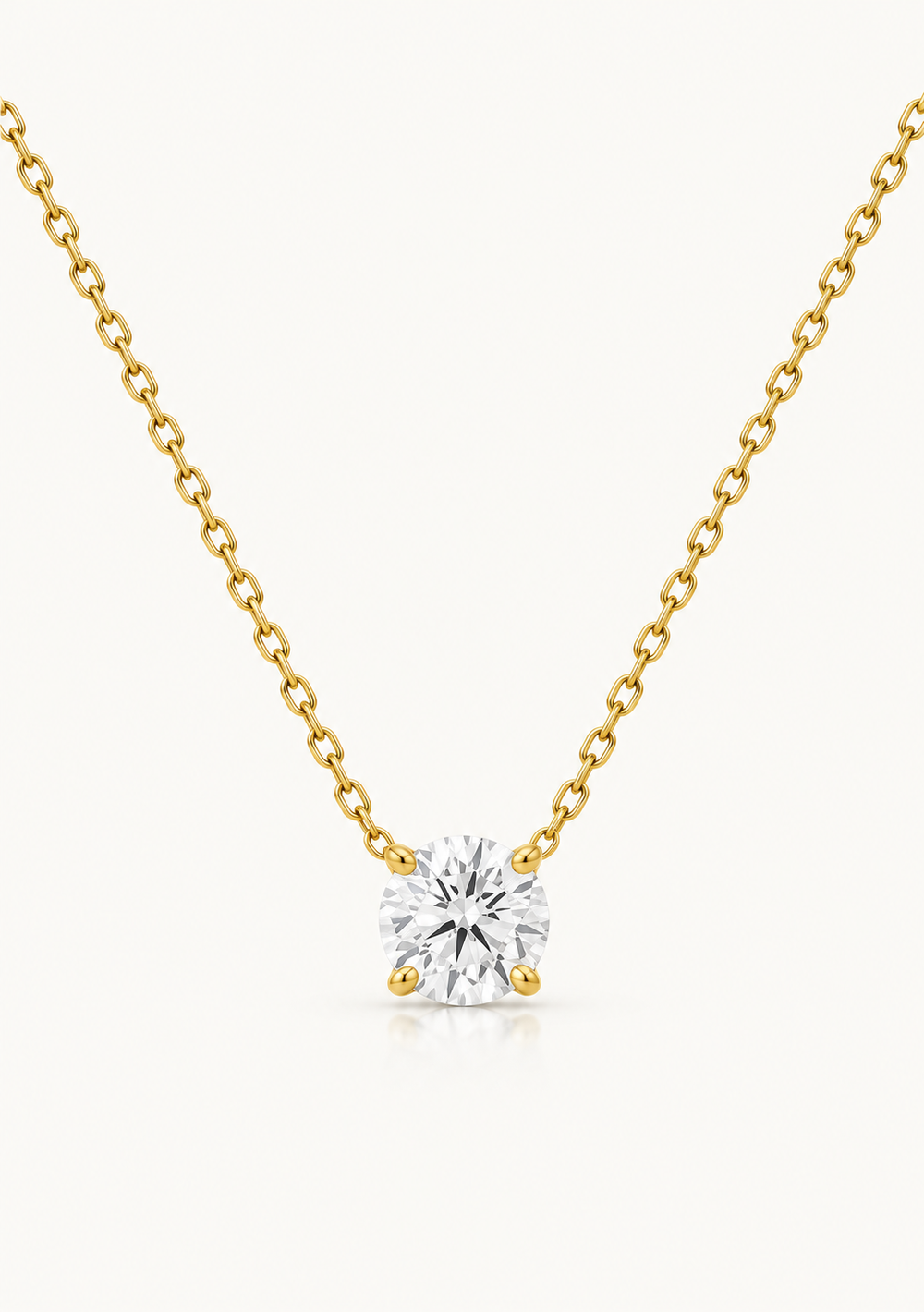 A delicate yellow gold chain necklace with a single solitaire diamond pendant, set against a clean off-white background.