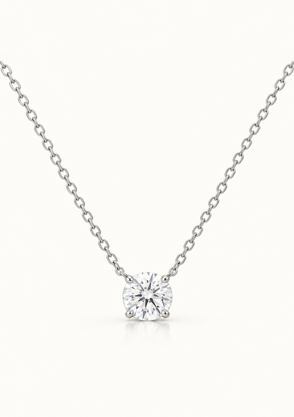 A classic solitaire diamond necklace featuring a round brilliant-cut diamond pendant on a delicate silver chain, set against a clean white background.