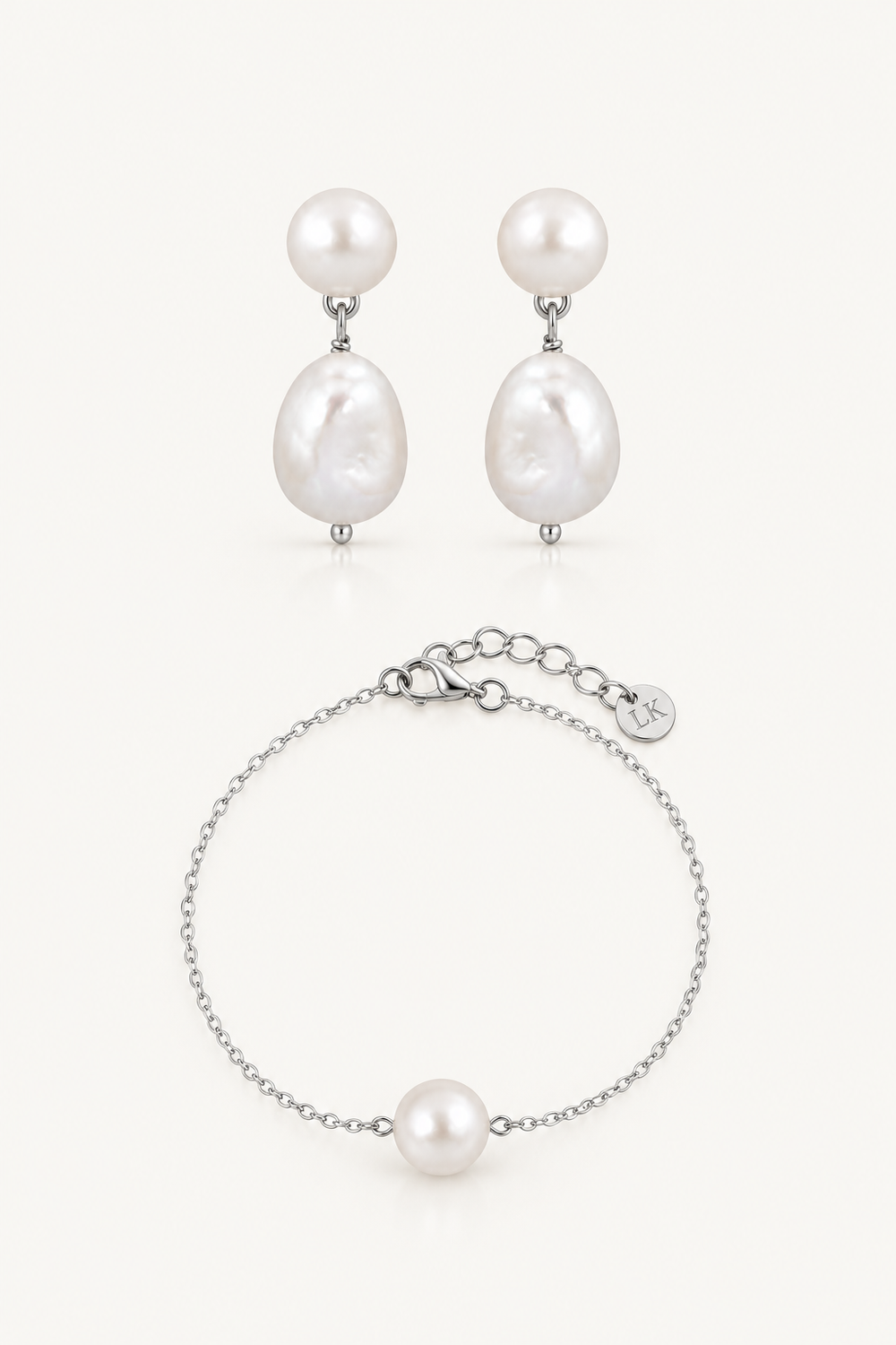 A jewelry set featuring a pair of drop earrings and a matching chain bracelet, both adorned with large white baroque pearls and silver-toned metal settings, displayed on a clean off-white background.