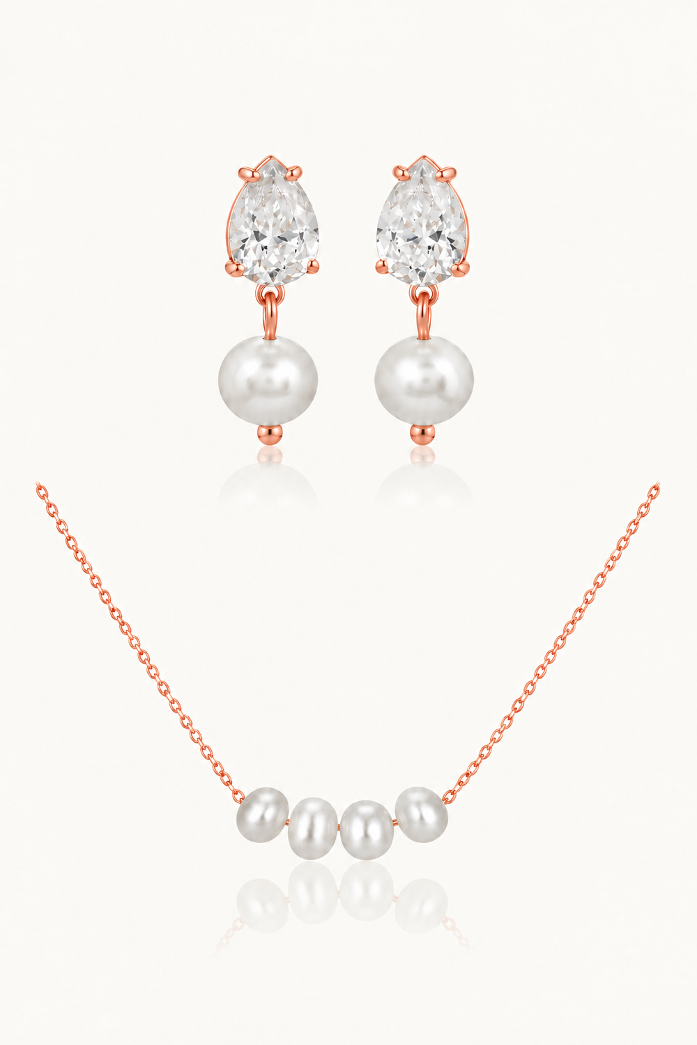 Rose gold jewelry set featuring a necklace and matching earrings with white freshwater pearls and clear pear-cut gemstones, displayed on a light cream background with soft reflections.