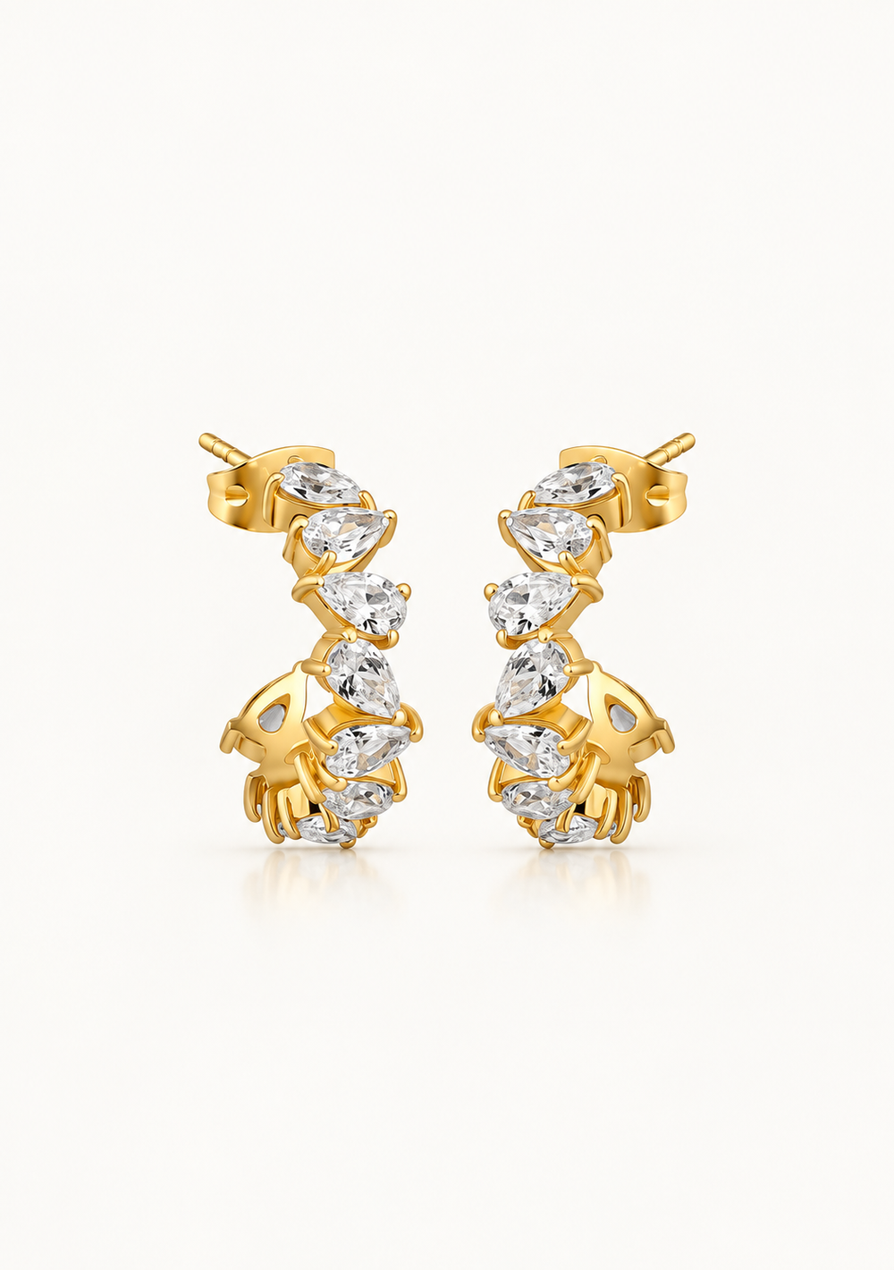 A pair of gold huggie hoop earrings adorned with marquise-cut clear gemstones, set against a clean white background.