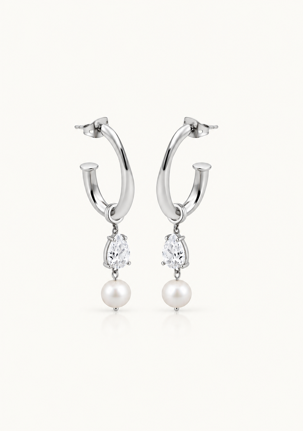 A pair of silver hoop earrings with marquise-cut clear stones and white pearls hanging below, shown on a clean off-white background.