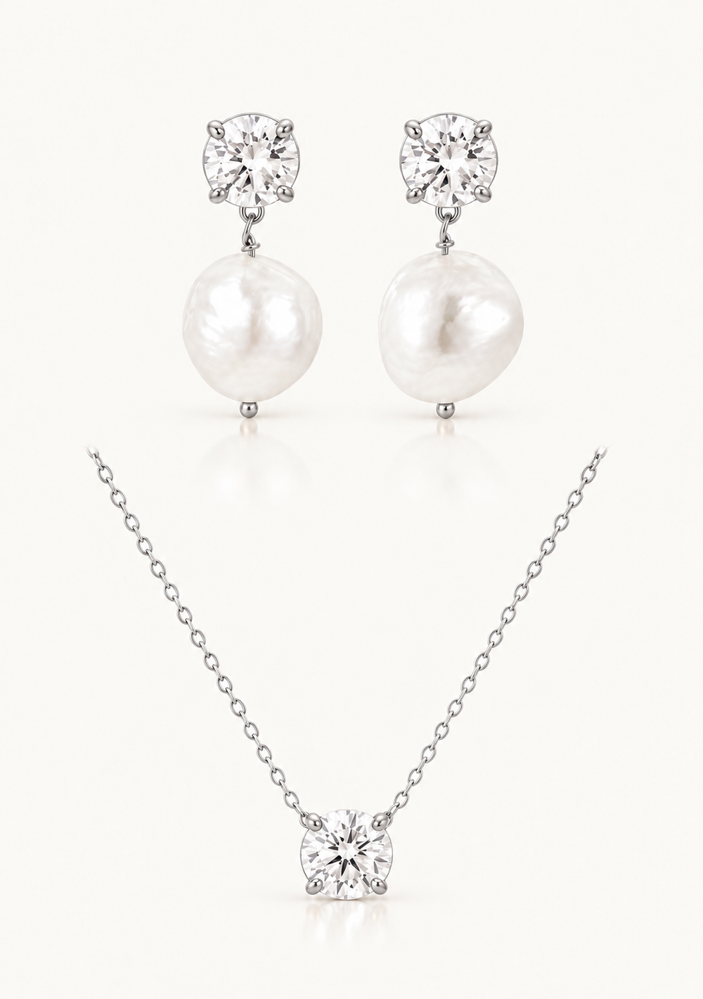 A jewelry set featuring a silver-tone necklace and matching drop earrings, each with a clear round gemstone and a large white pearl pendant, displayed on a light cream background.