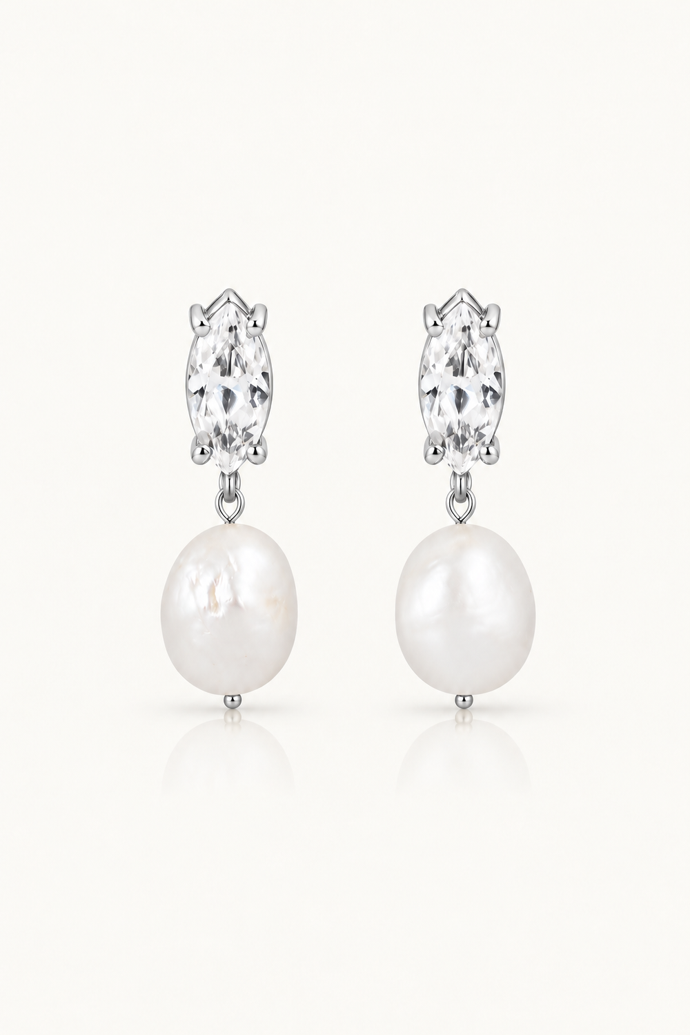 A pair of silver pearl drop wedding earrings featuring marquise-cut clear crystals above large white freshwater pearls, set against a clean off-white background.